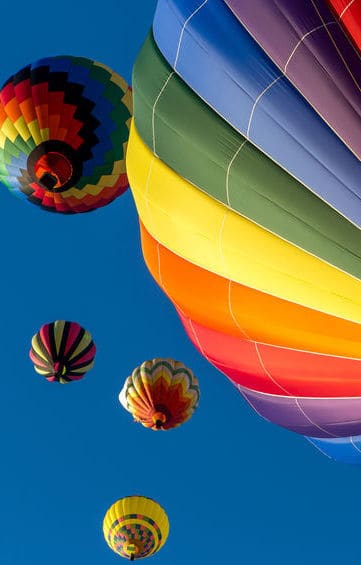 Colorful hot air balloons flying in the bright blue sky at the Festival of Ballooning in New Jersey.