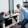Woman truck driver checking her trailer seal number - Discover Tulsa gooseneck trailer locks in tulsa